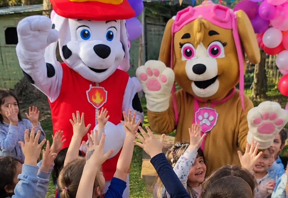 Personajes corpóreos saludando a un grupo de niños con las manos en alto