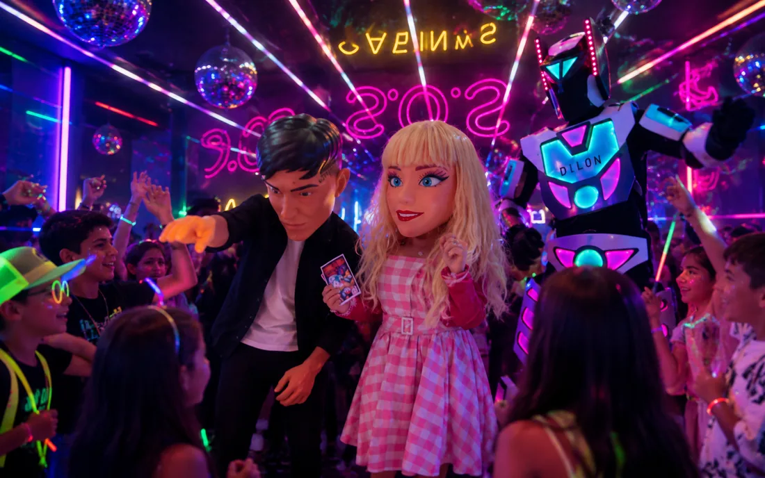 Fiesta con luces de neón, personajes y robot LED rodeados de chicos bailando