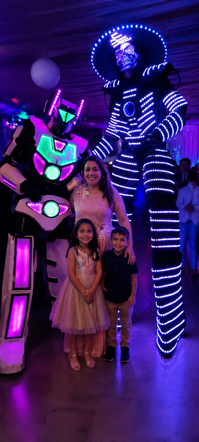 Robot LED blanco y robot LED mexicano posando con una familia en una fiesta